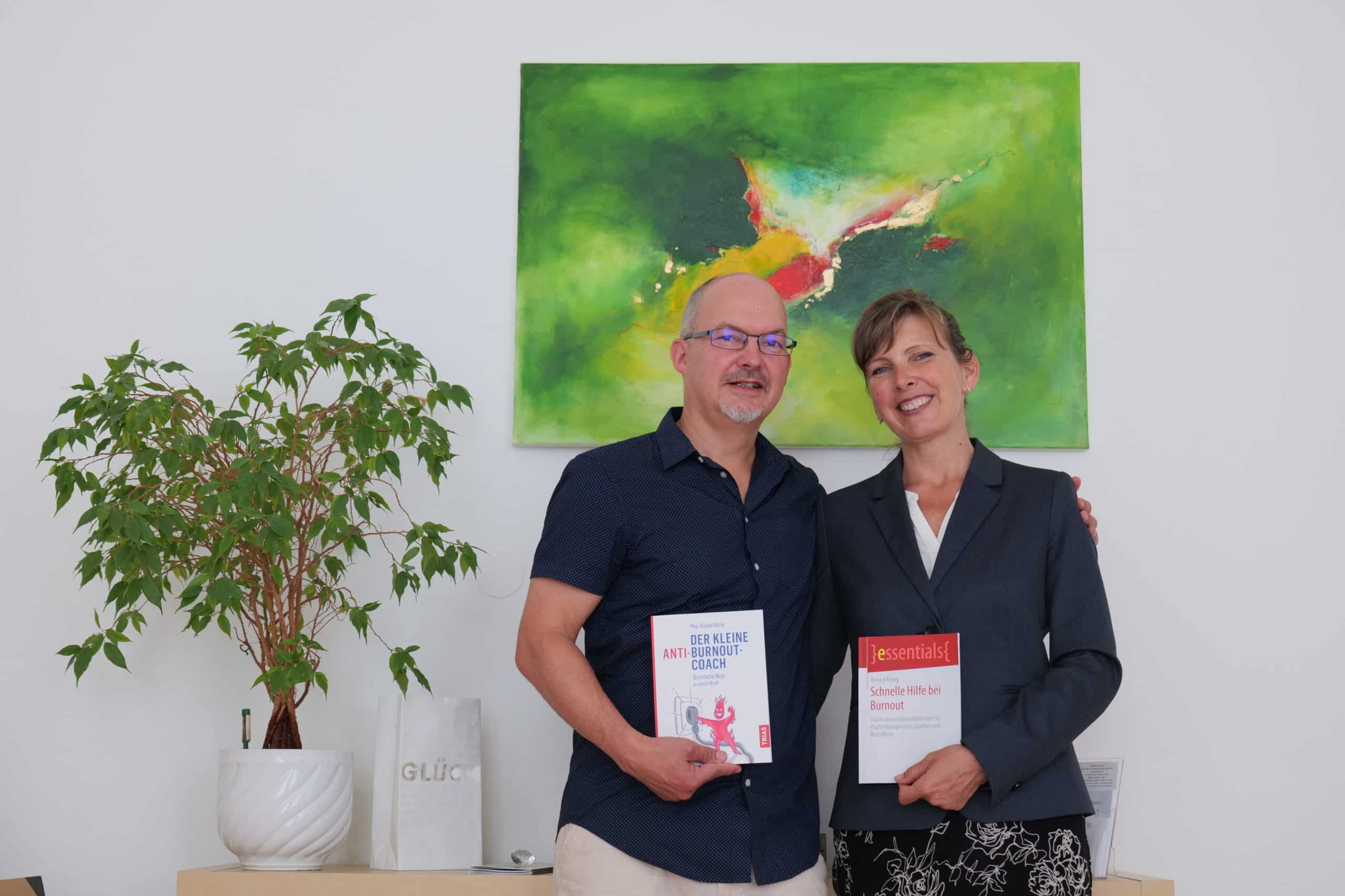 Roland K&ouml;nig with colleague and their published books in the practice